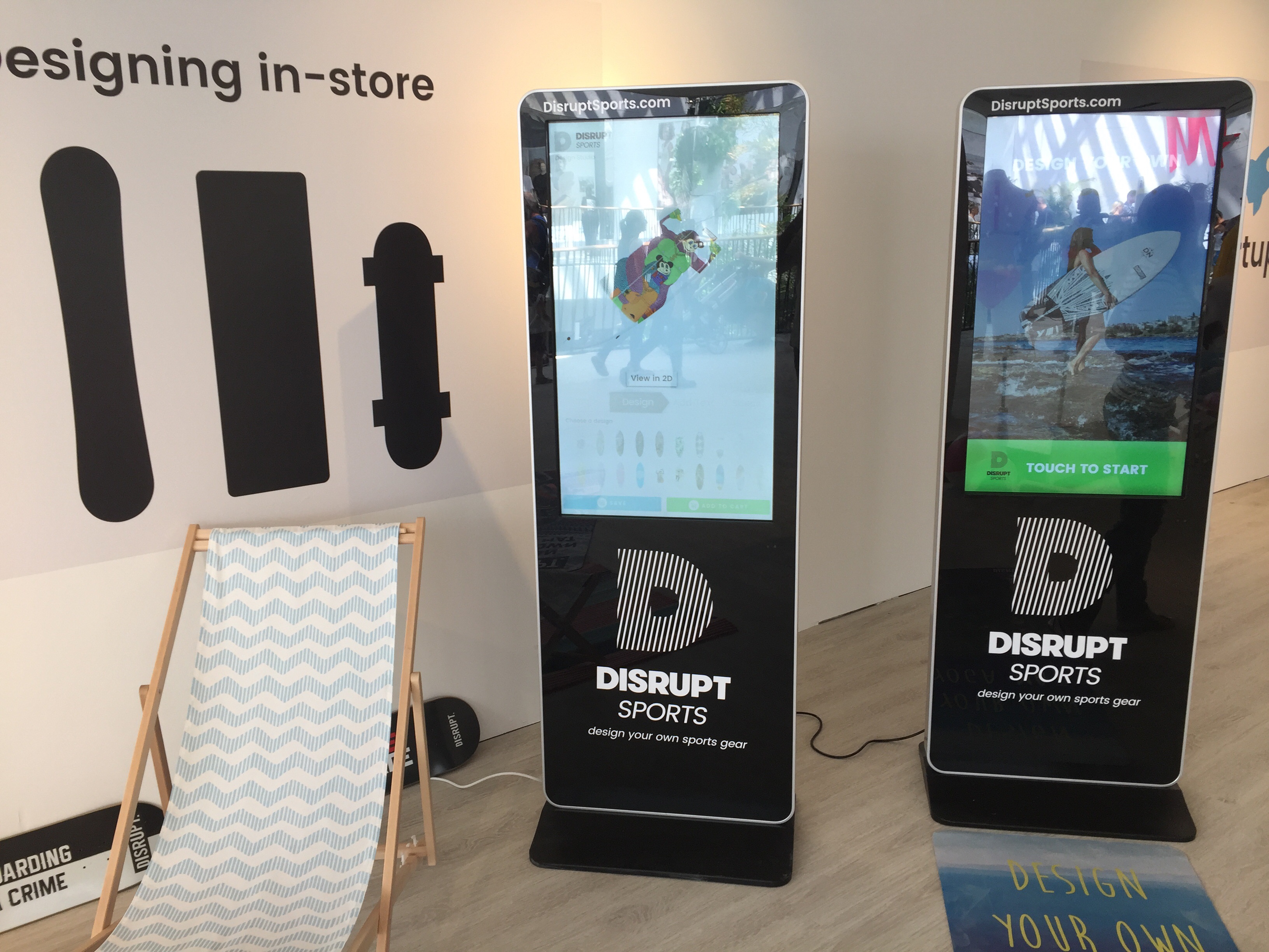 Image of a kiosk, a large touch screen device with a surfboard on it.
